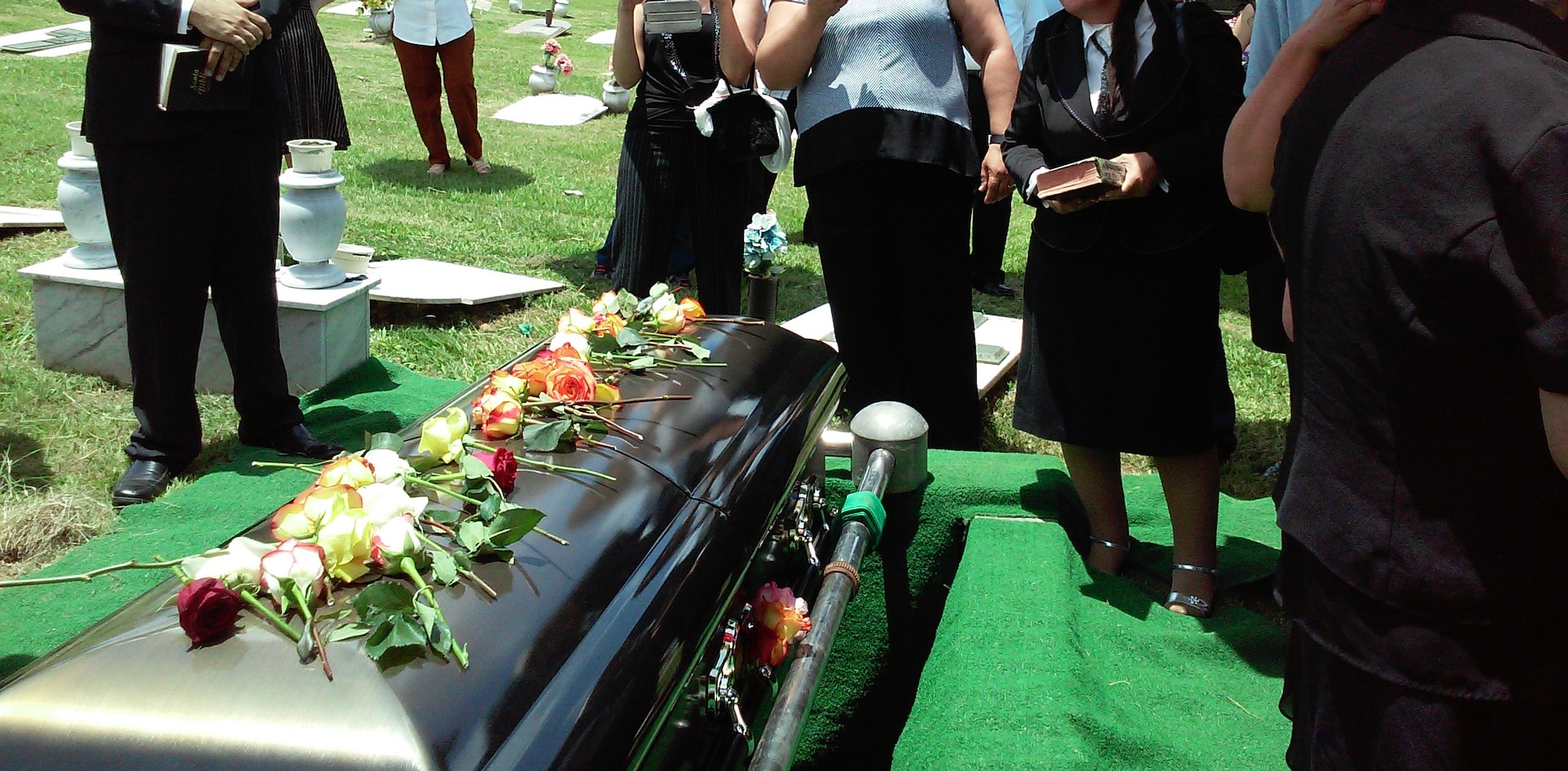 Dressing for a funeral. Image of people dressed in black around a casket