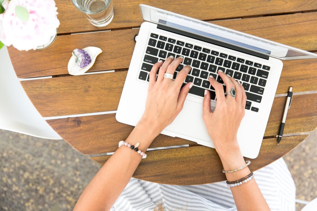 A woman's hands writing something on a laptop to accompany article by Delia Lloyd a blogger about adulthood