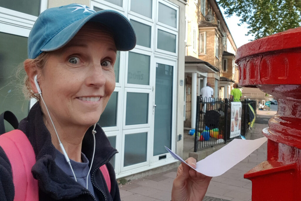 Delia Lloyd posting her postal vote in a British red post box